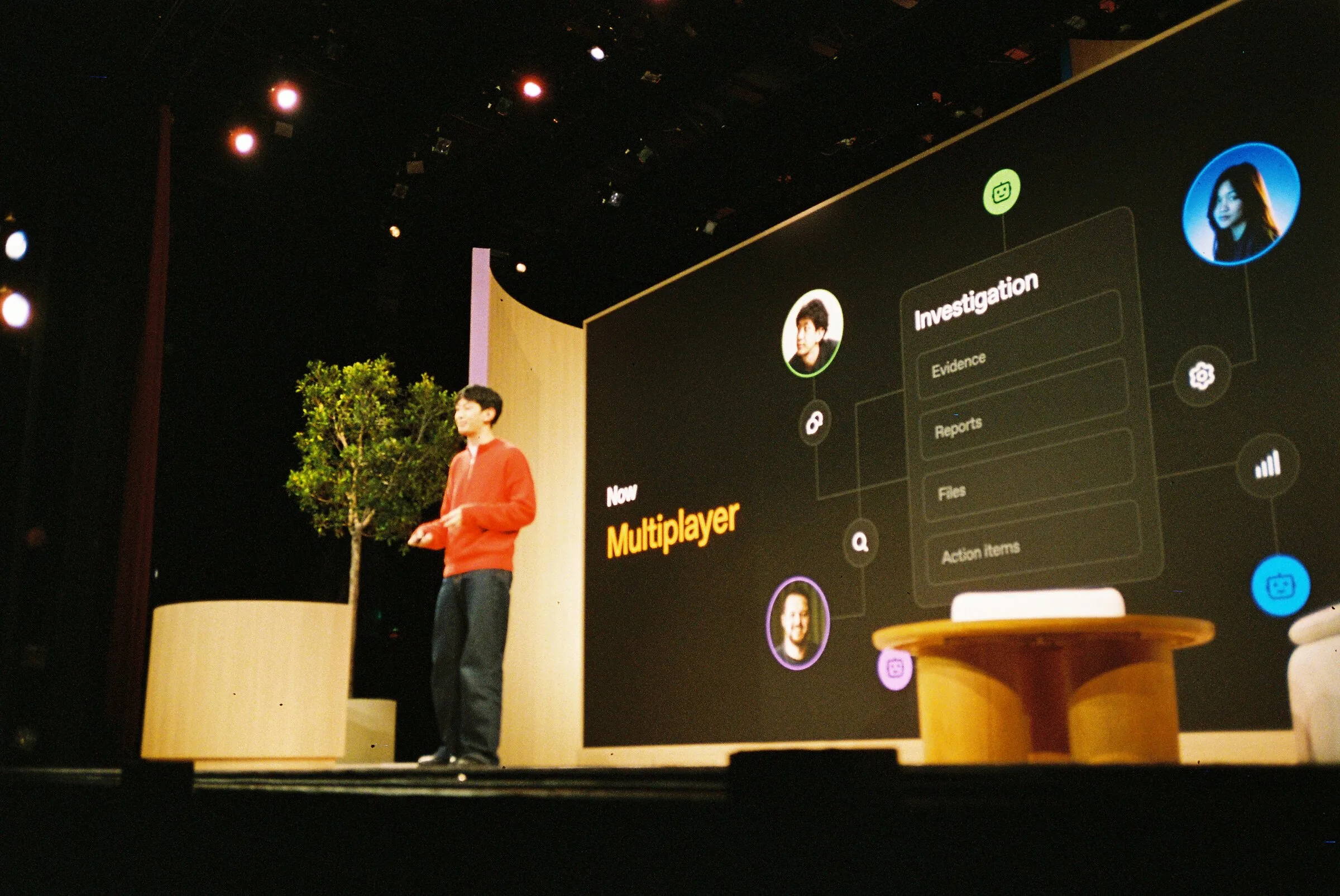 A speaker on a dark stage in front of a screen reading Multiplayer