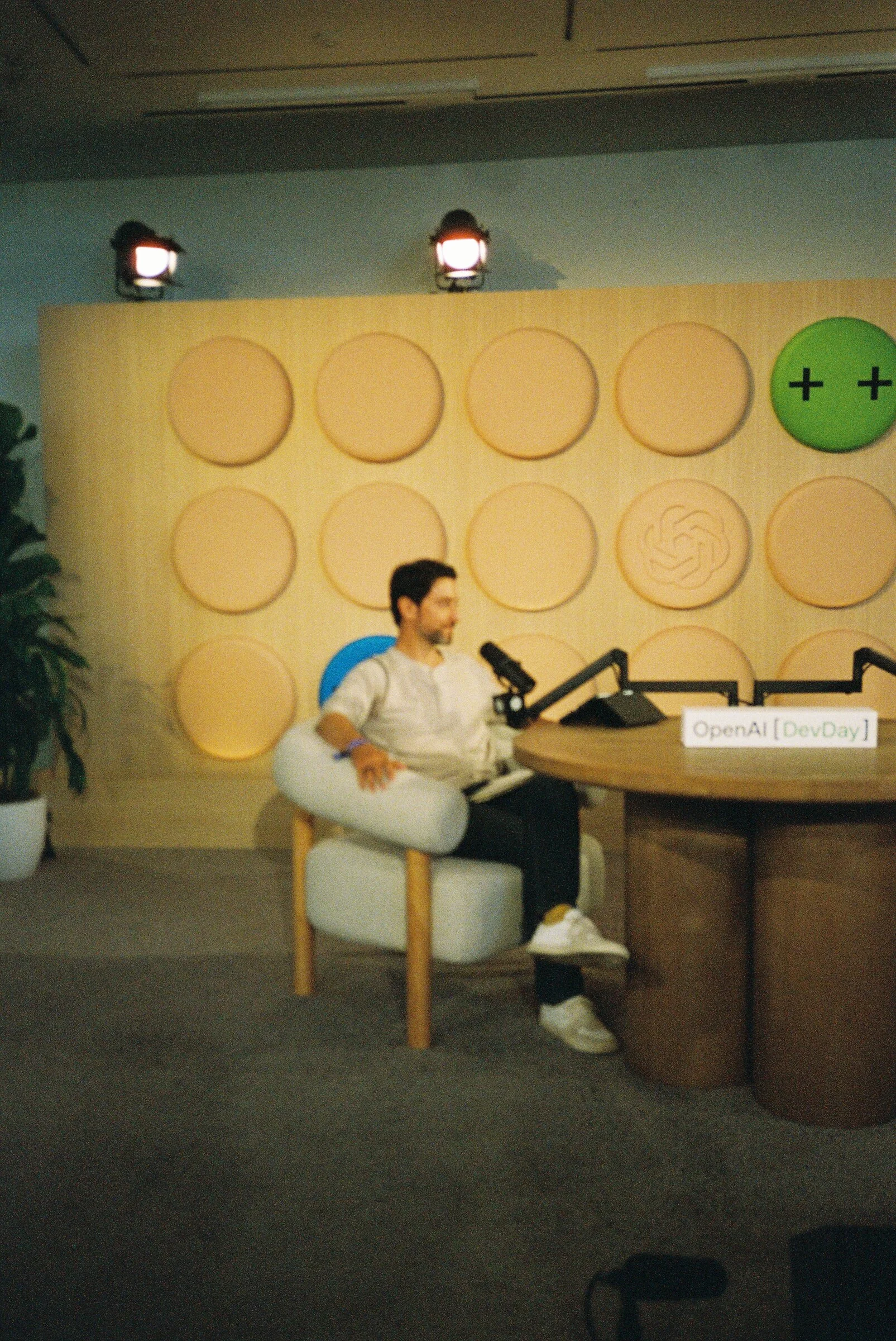 A man seated in a white armchair on the podcast set