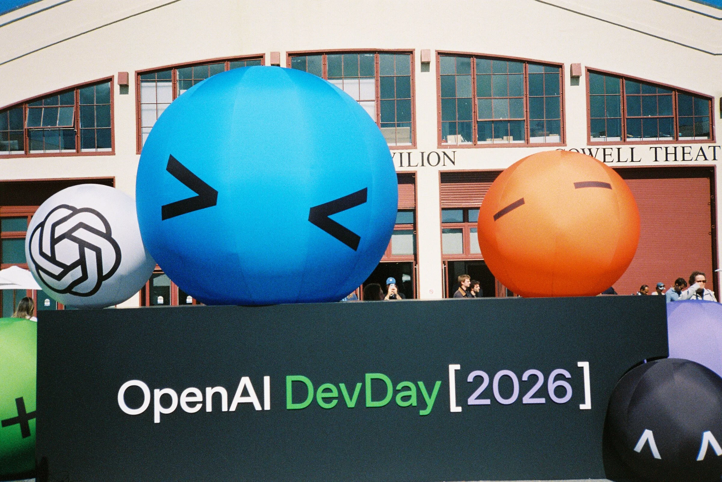 Giant inflatable faces above an OpenAI DevDay 2026 sign