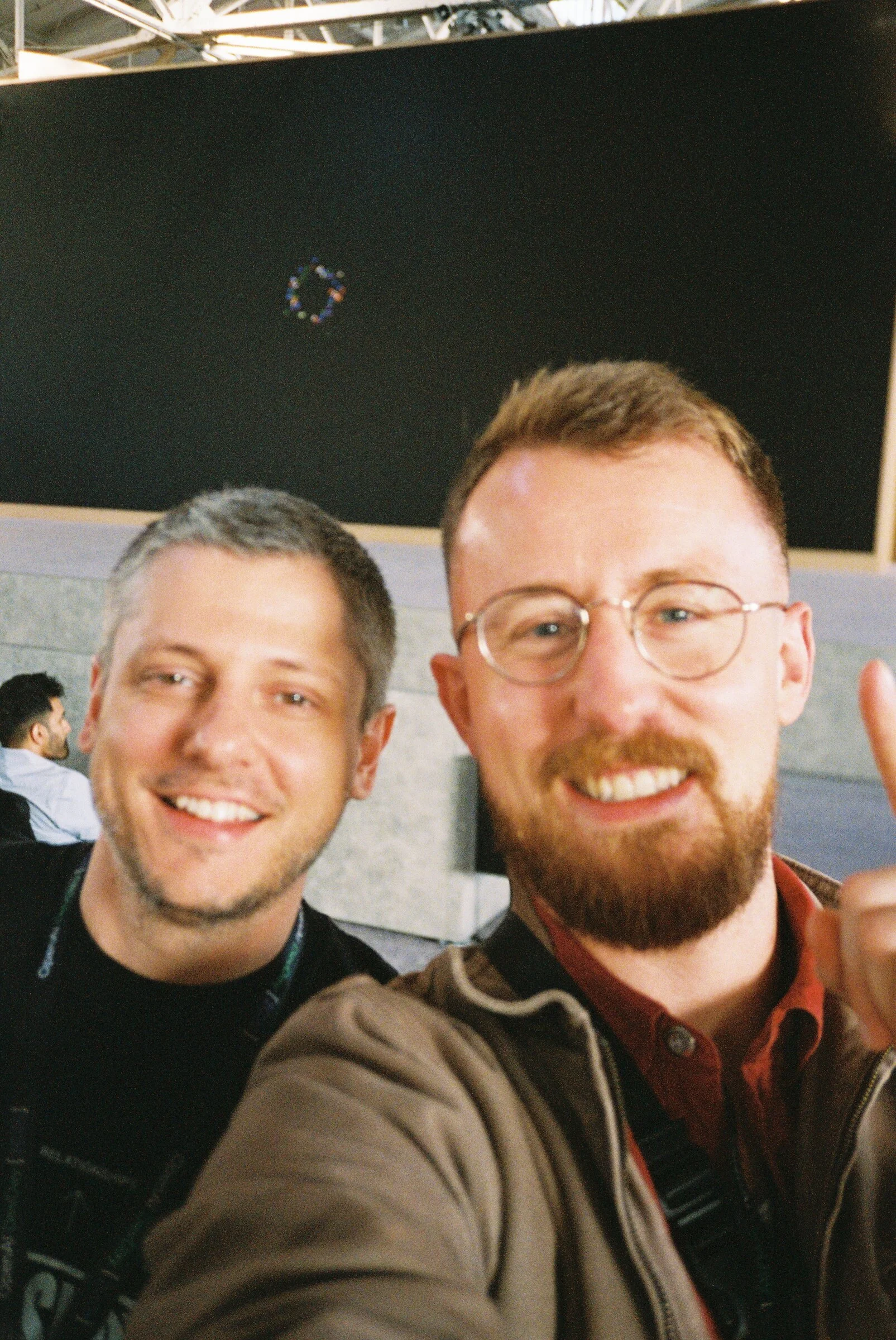 A close-up flash selfie of two smiling men
