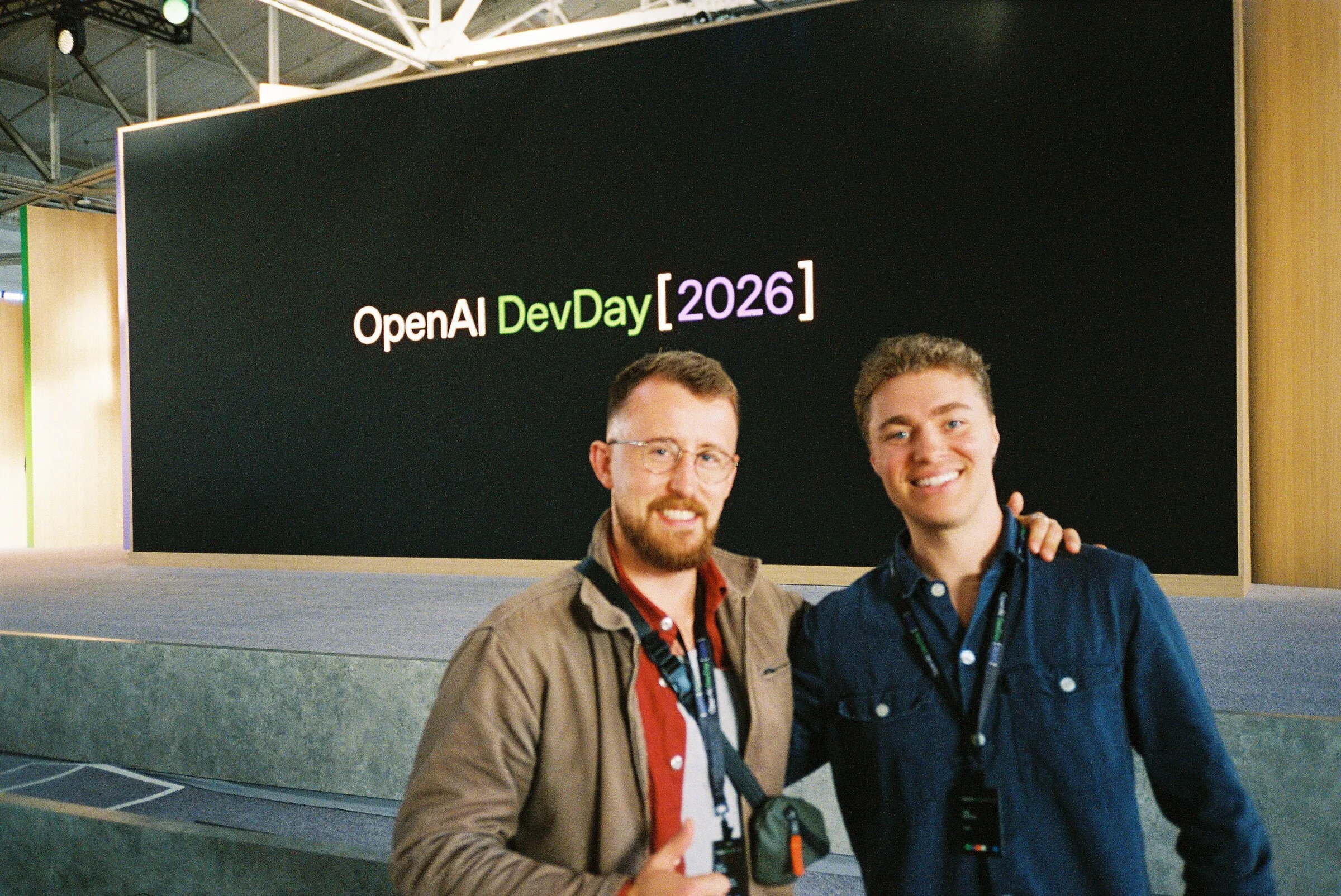 Two men posing in front of the DevDay 2026 screen