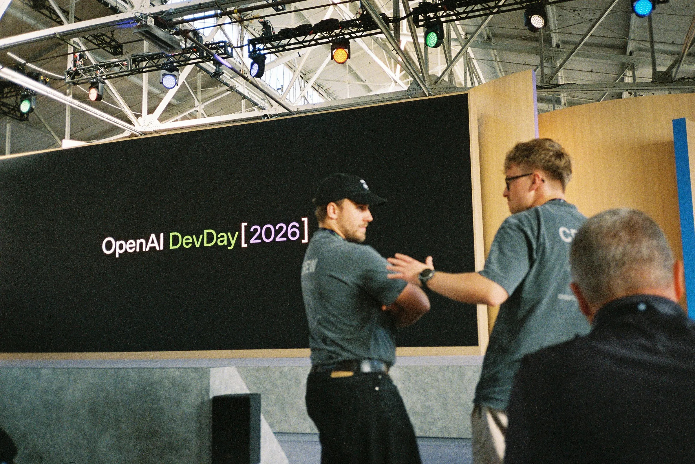 Two men shaking hands on stage in front of the DevDay 2026 screen