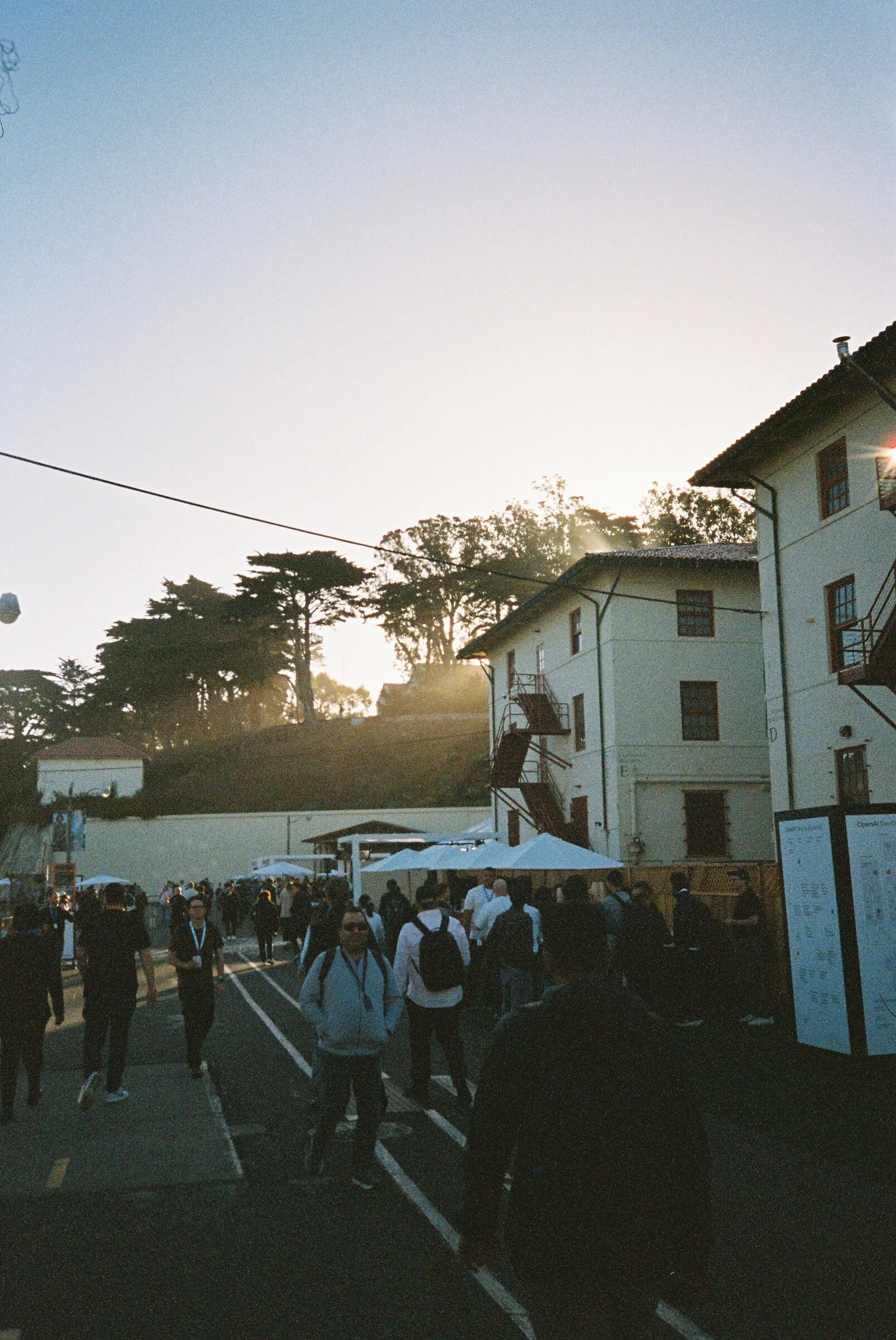 Attendees walking between old military buildings at golden hour