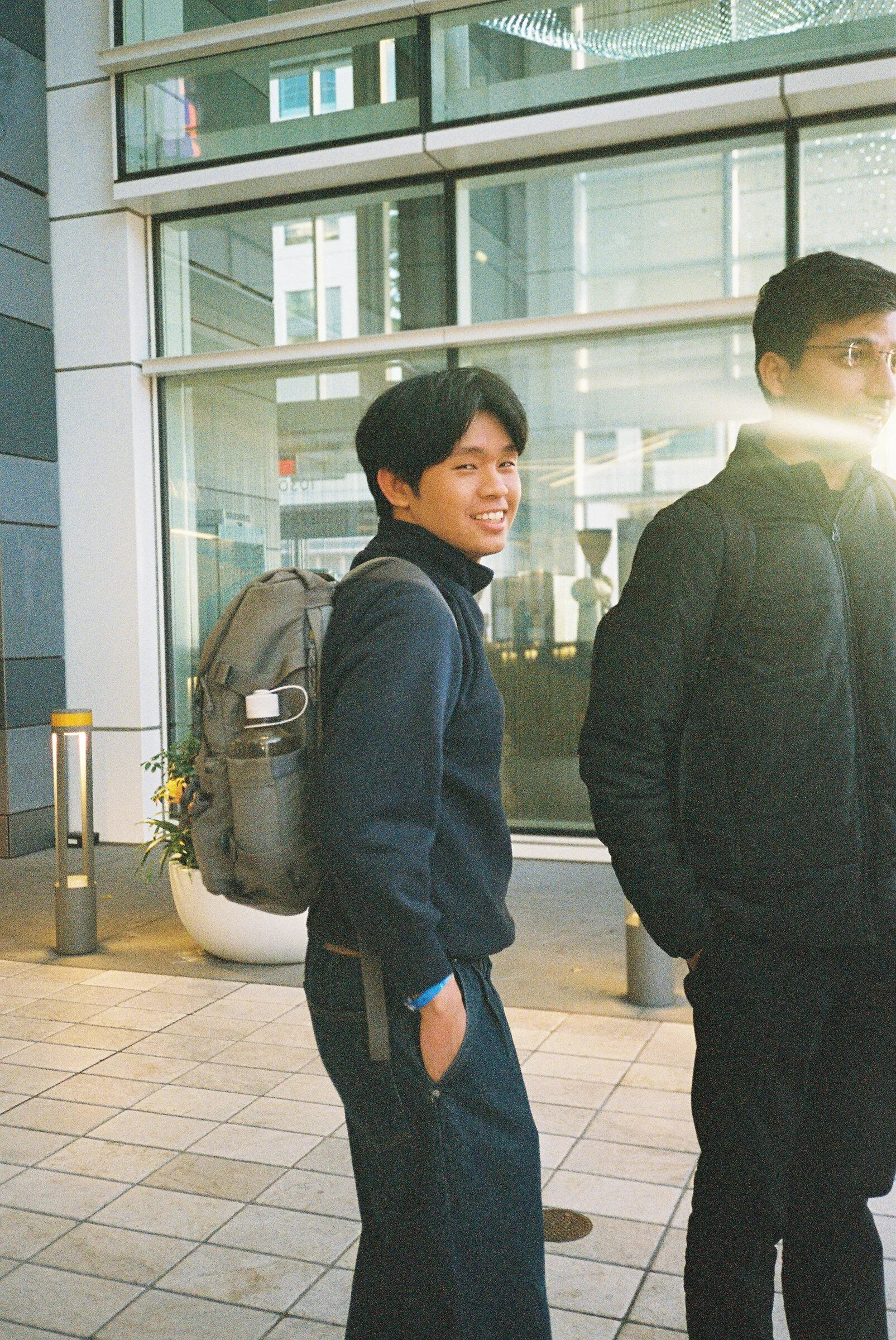 A man with a backpack outside a glass-fronted building