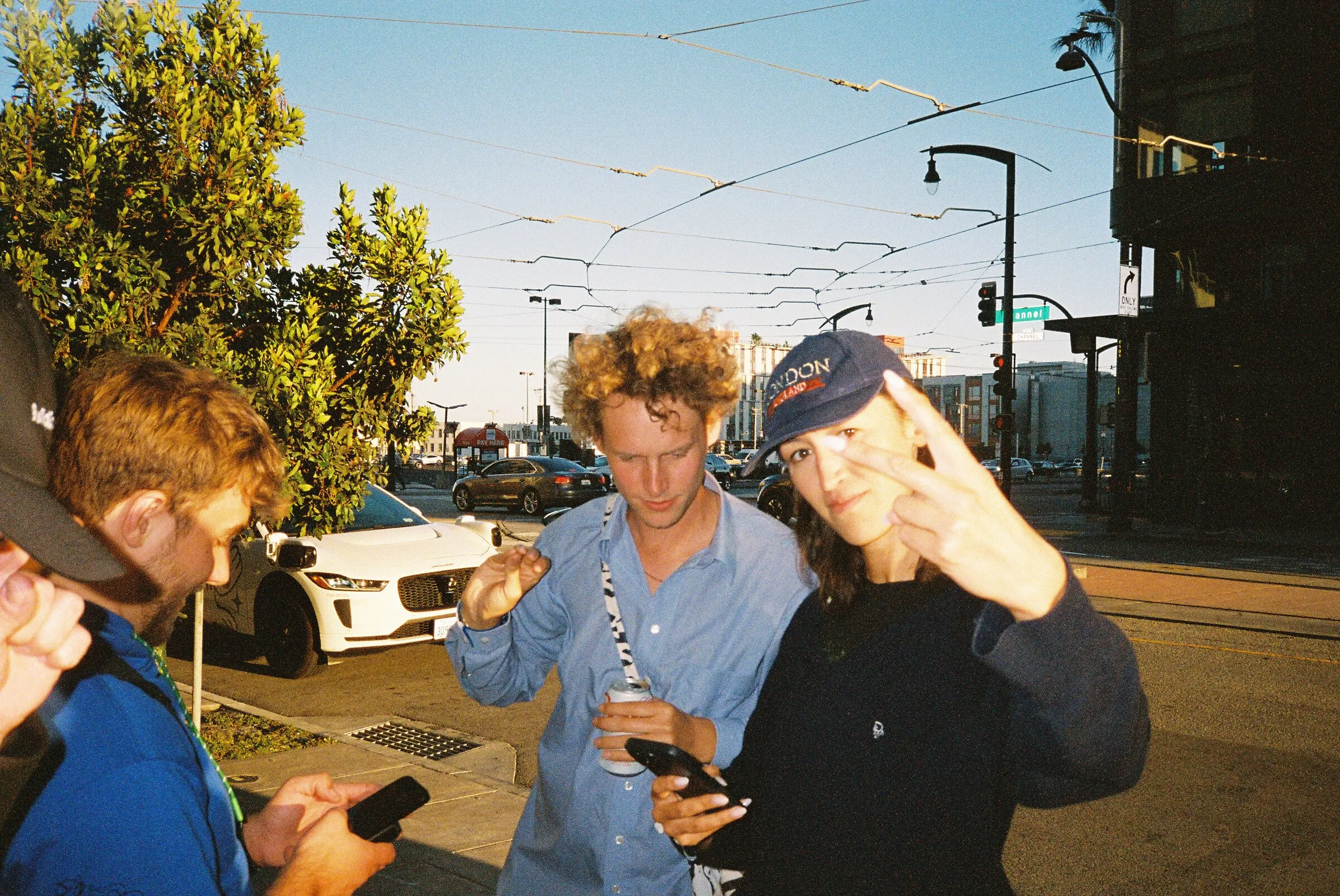 Three friends laughing on a street corner in evening sun