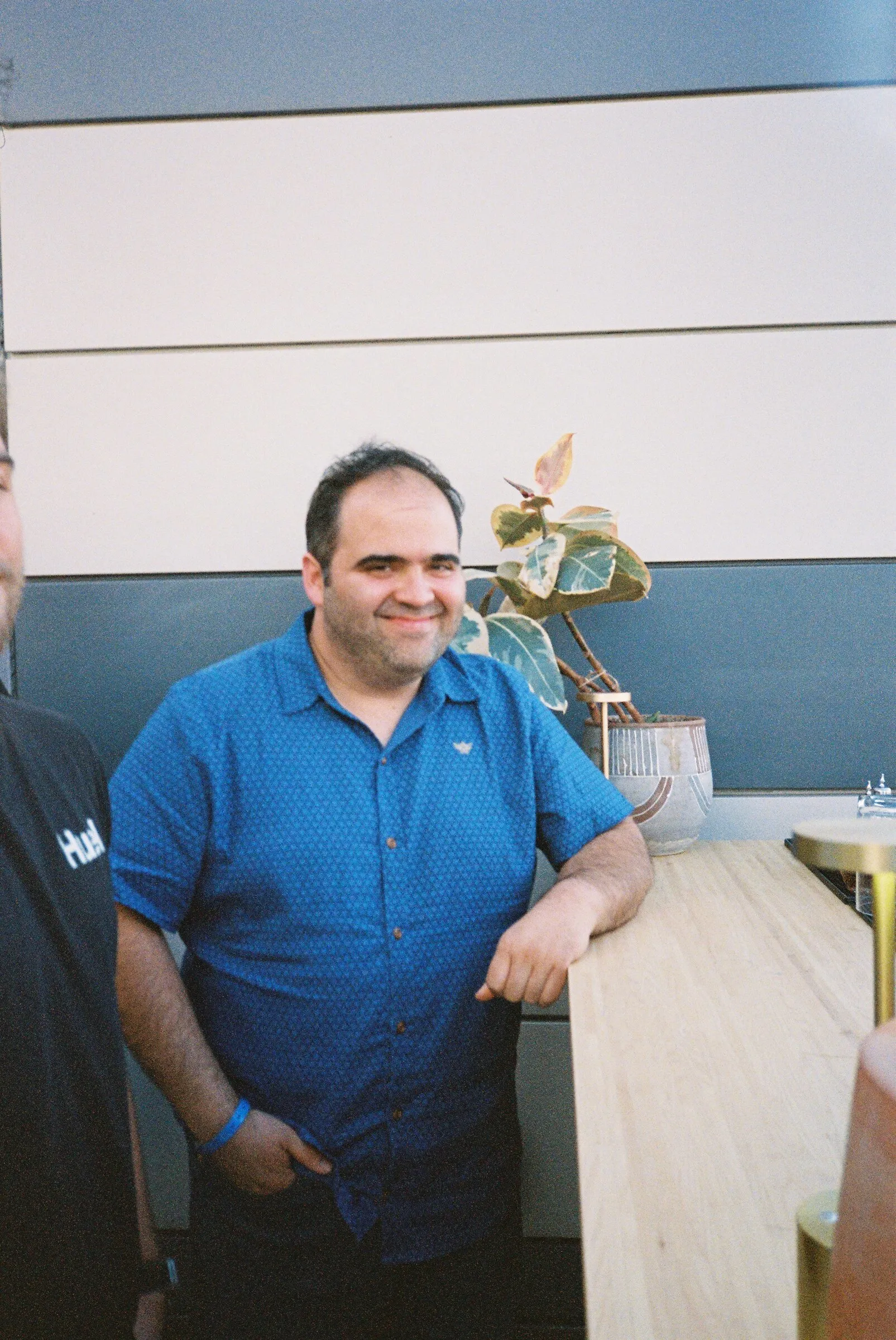 A man in a blue shirt leaning on a counter