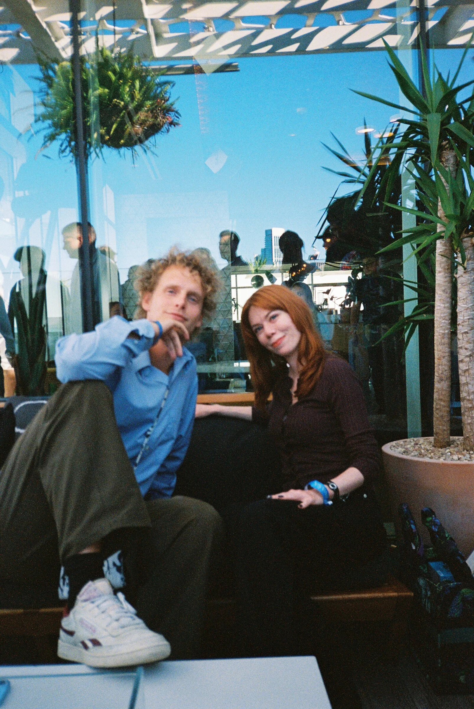 Two people relaxing on a terrace bench among plants