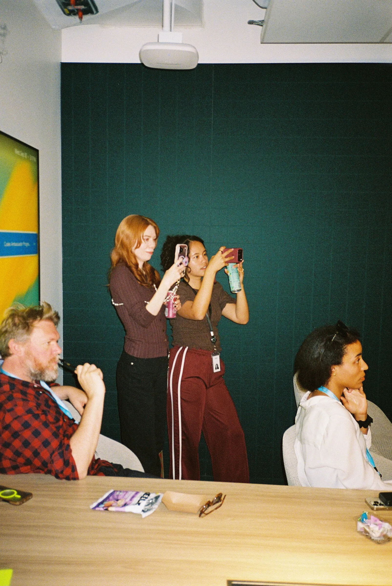 People taking photos in a room with a dark green wall