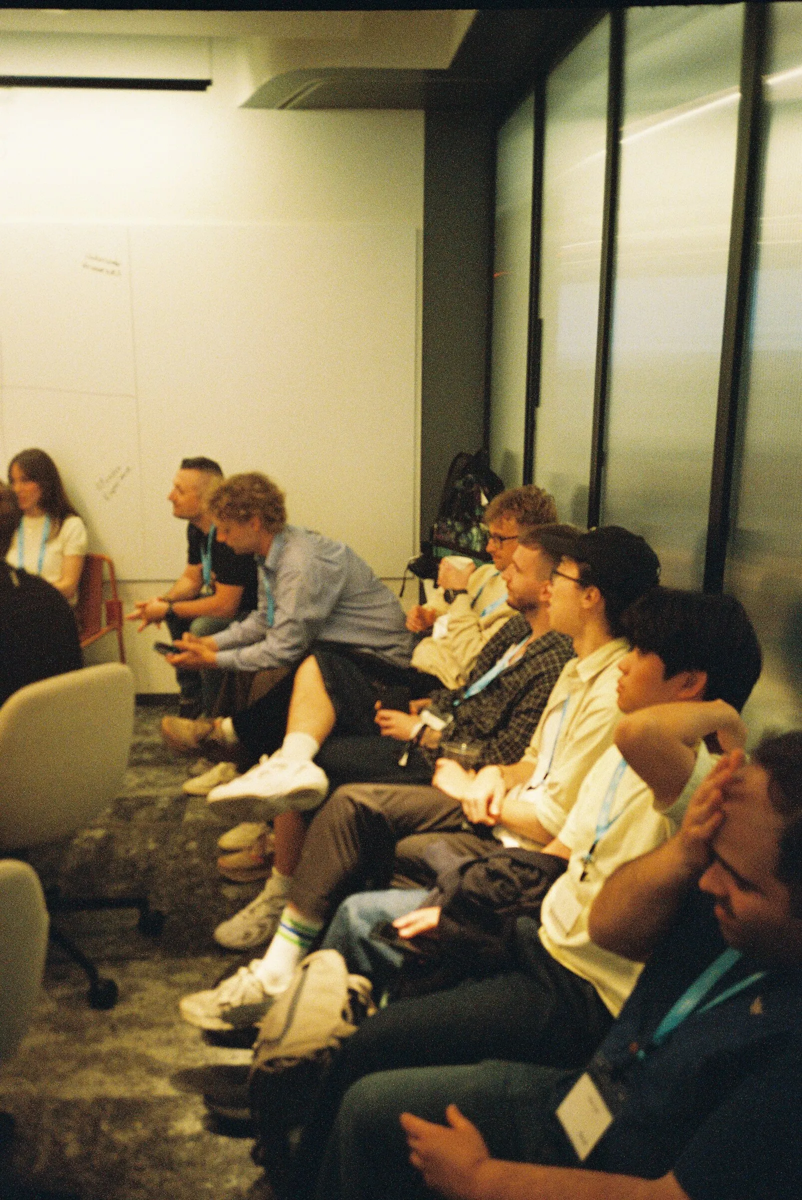 People sitting along a sofa in a dim corridor