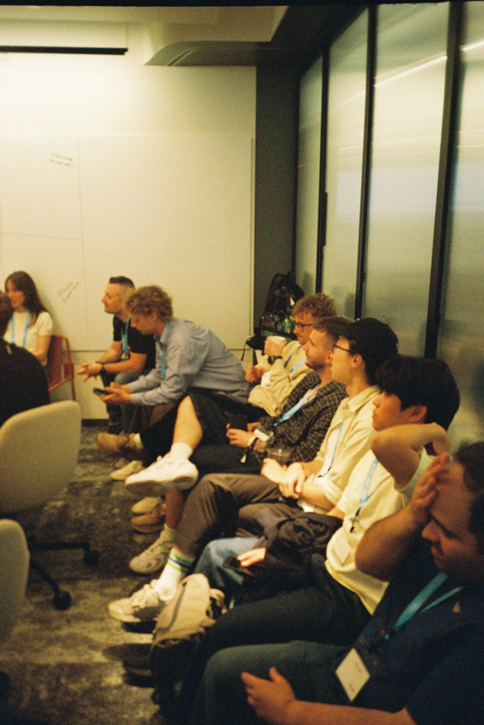 People sitting along a sofa in a dim corridor