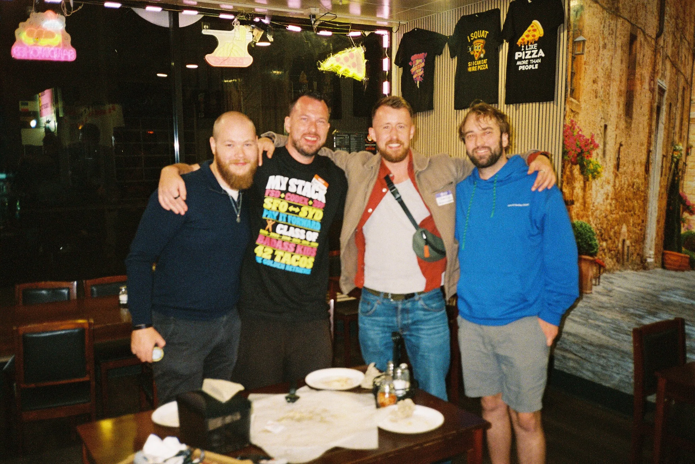 Four men posing together in a bar