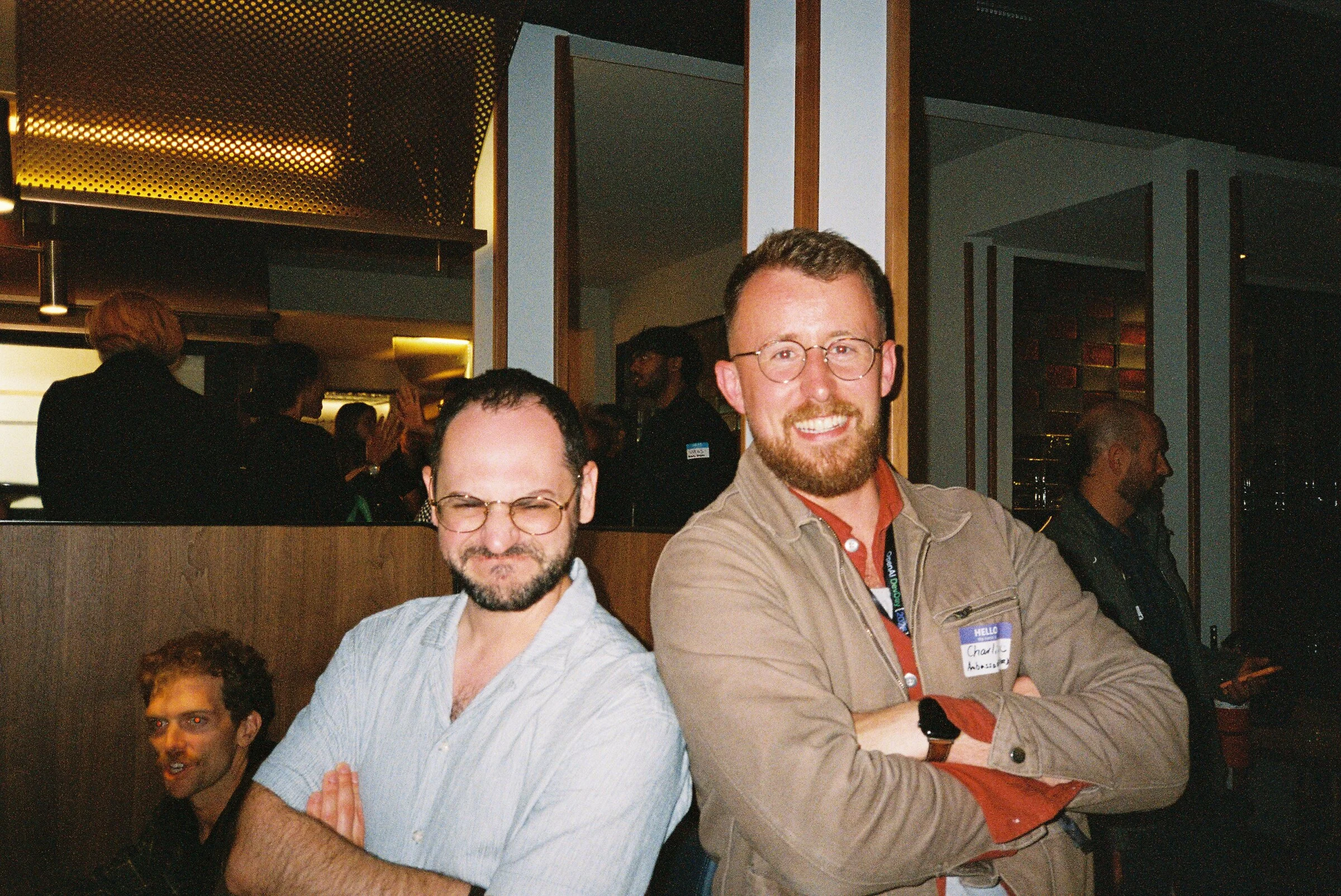 Two men smiling in a busy restaurant