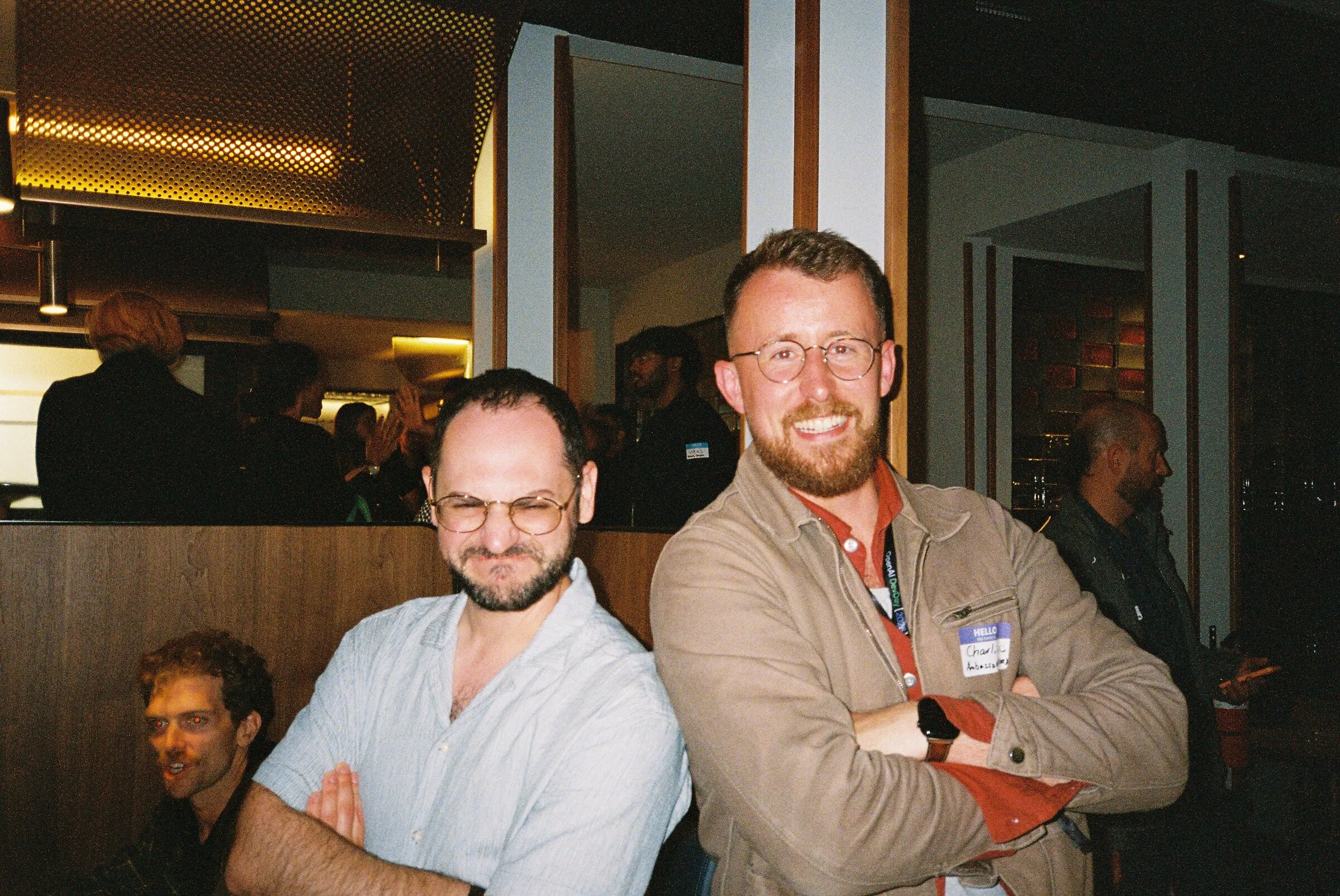 Two men smiling in a busy restaurant