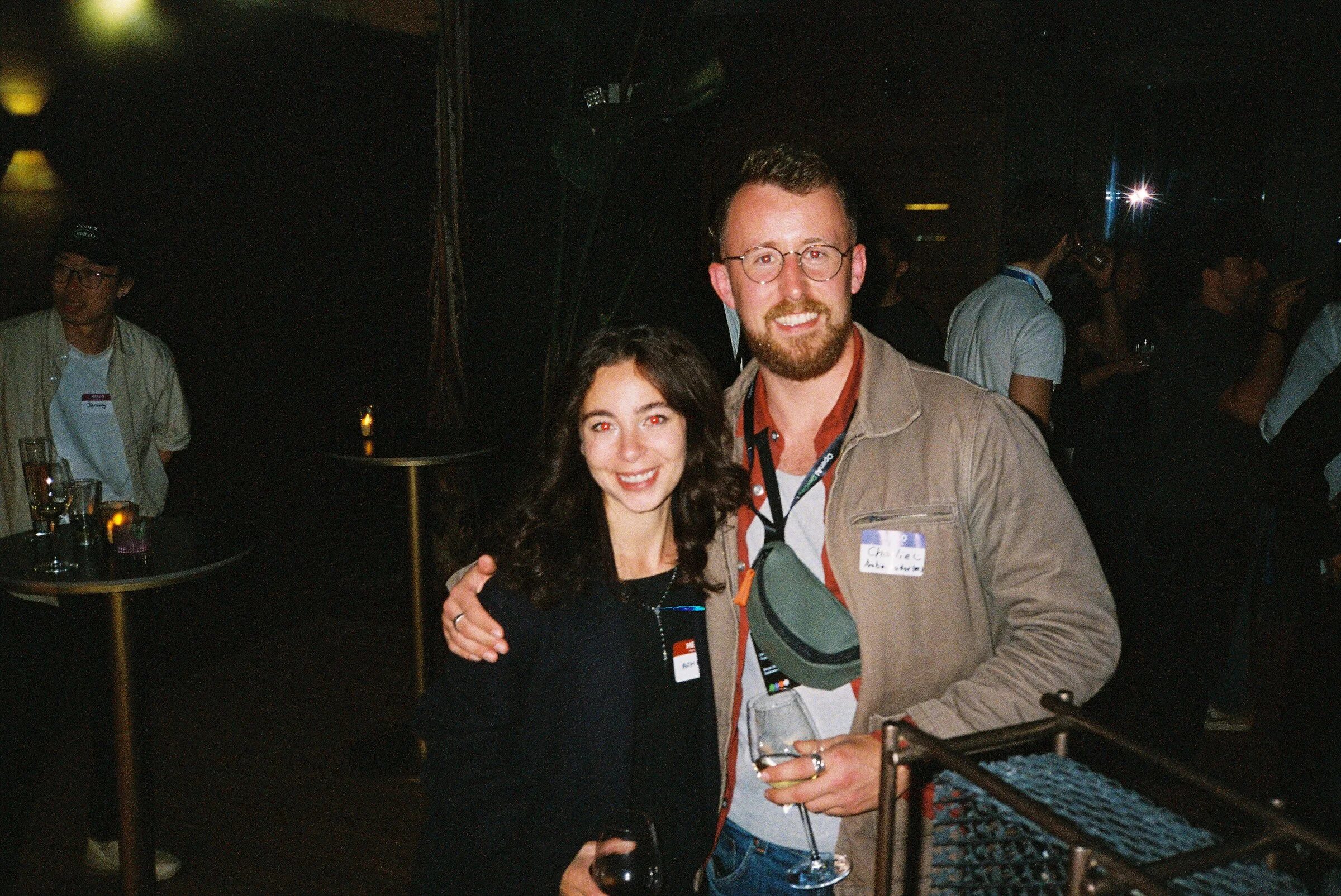 A man and a woman posing together in a dark bar