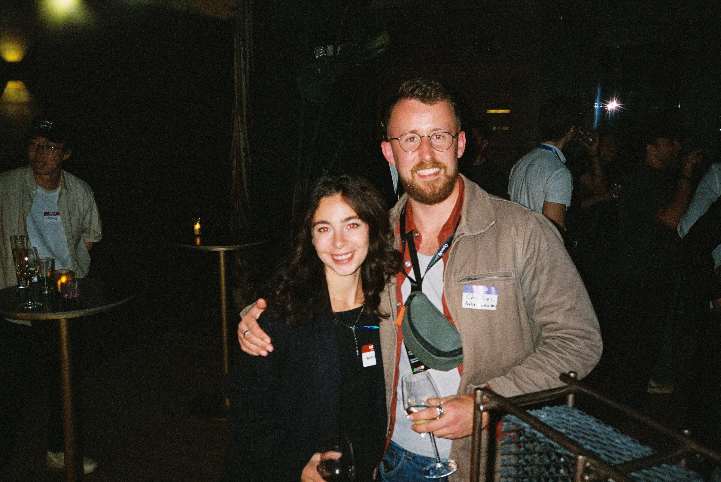 A man and a woman posing together in a dark bar